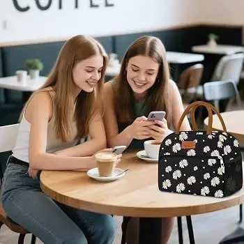 Two women at a cafe table beside a black floral Coobiiya lunch bag
